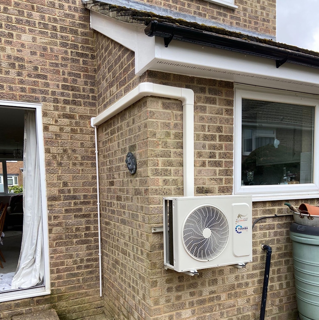 12000 BTU wall mounted air conditioning outdoor unit installed on an outside wall in a residential property lounge